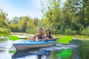 Family kayaking, mother and child paddling in kayak on river canoe tour, active autumn weekend and vacation, sport and fitness concept